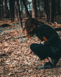 jeune femme accroupie dans la forêt, dans les feuilles mortes