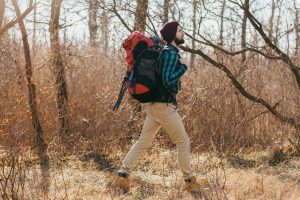 homme qui marche avec un sac à dos dans la nature, de profil